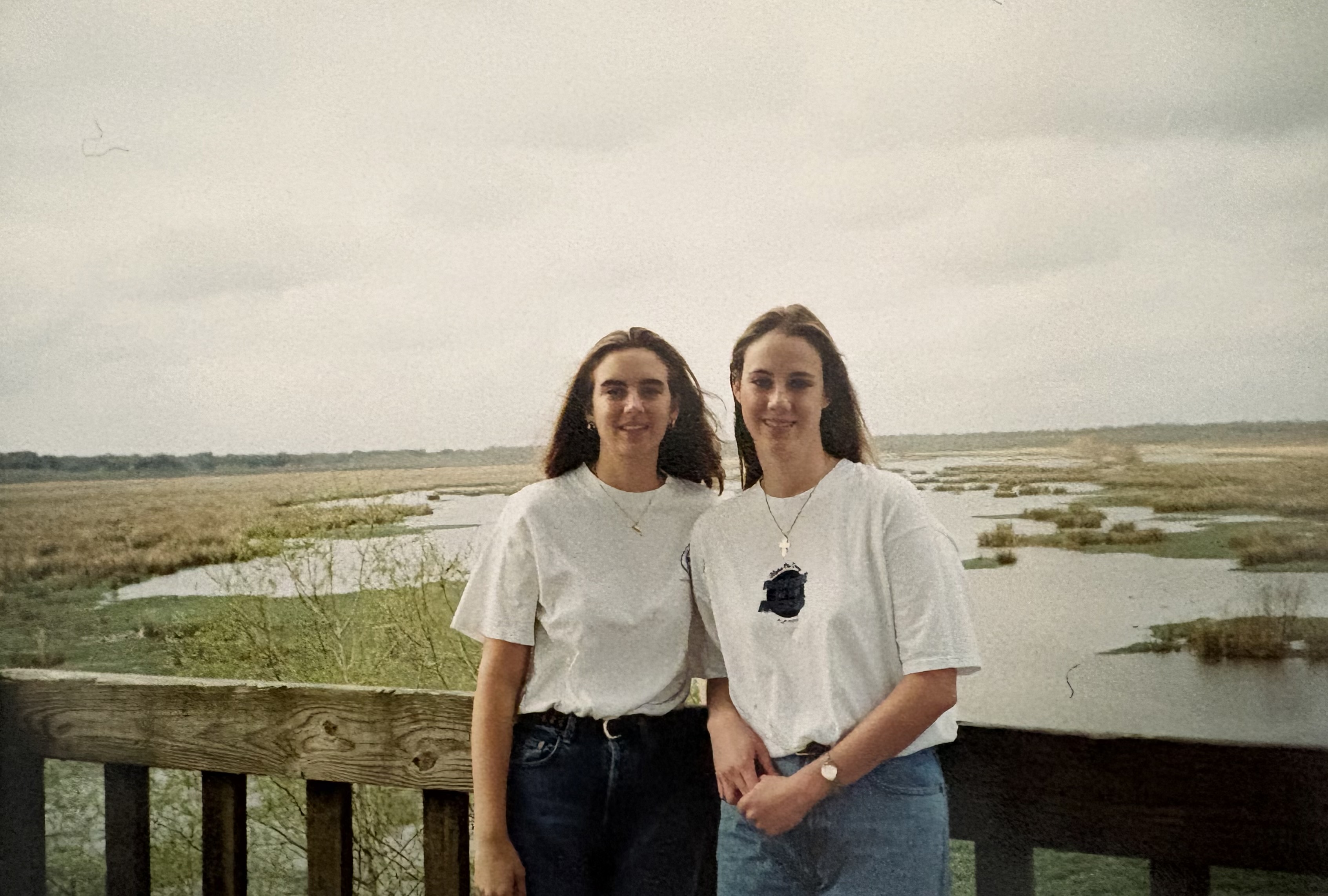 Two women standing in front of a body of water