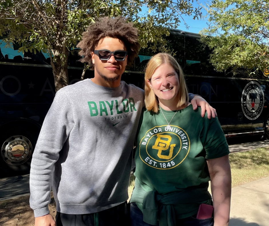 A man and a woman standing next to a tour bus