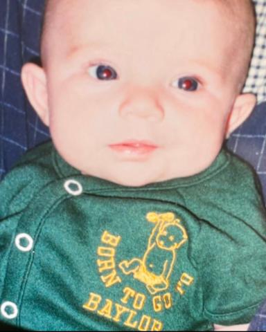 Anna Johnson as a baby with a onesie that reads "Born to go to Baylor"